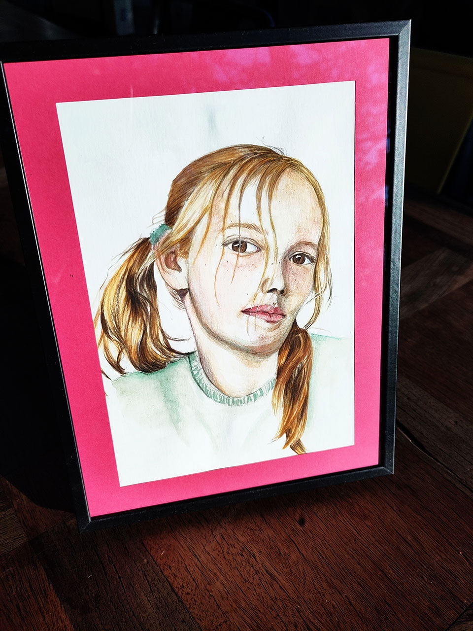 Portrait à l'aquarelle d'une jeune fille blonde avec des couettes dans un cadre